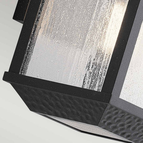Close-up of the Springfield Outdoor 1 Light Small Wall Lantern in black, featuring textured, frosted glass panels and a distressed finish. The design incorporates geometric shapes and a softly illuminated interior, while being IP44 rated for durability.