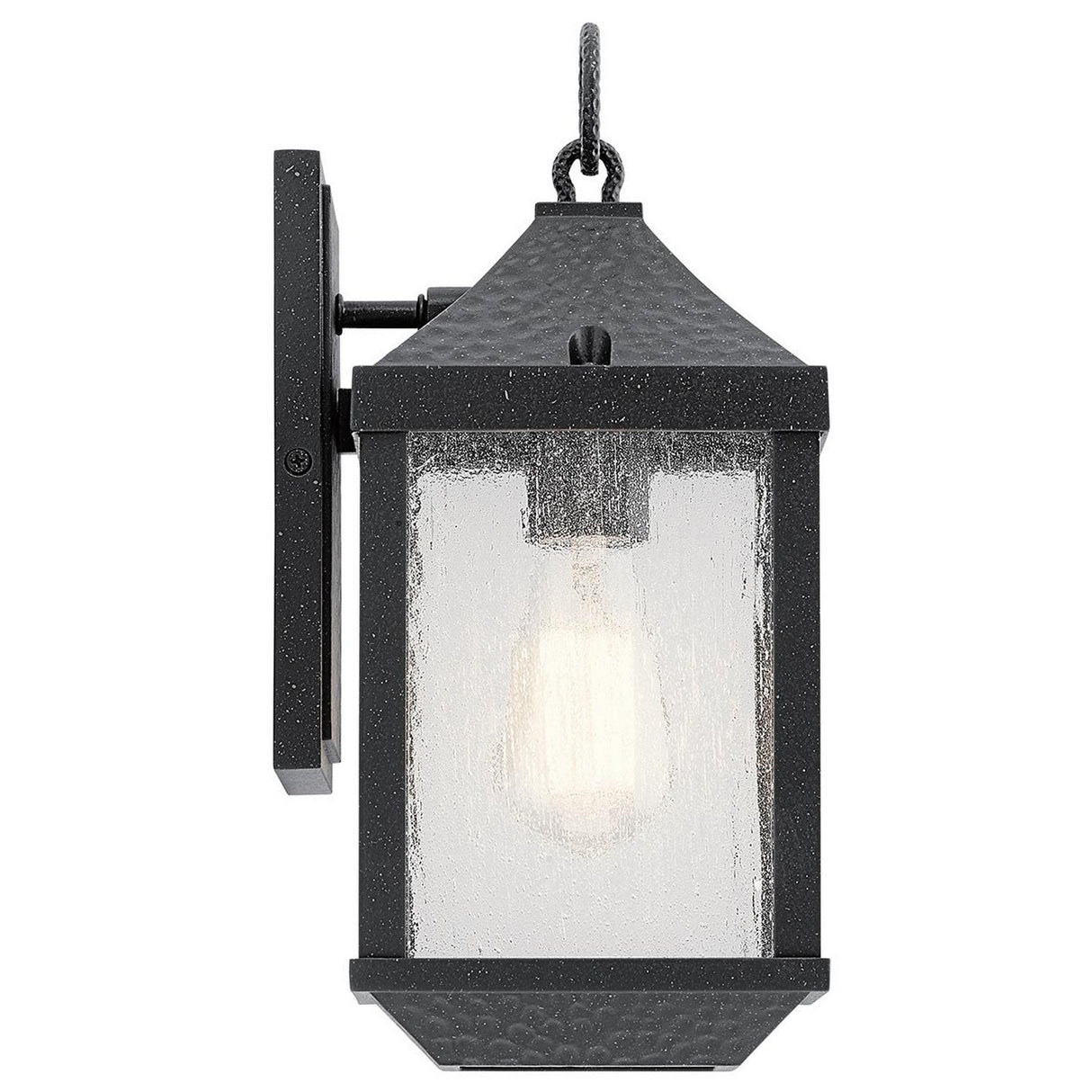 The Springfield Outdoor 1 Light Small Wall Lantern - Black is a stylish black metal fixture with a distressed finish and textured surface. It features clear glass casing that reveals the bulb inside, mounted on a rectangular backplate. With an IP44 rating, it combines classic and rustic design elements.