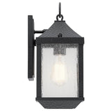 The Springfield Outdoor 1 Light Small Wall Lantern - Black is a stylish black metal fixture with a distressed finish and textured surface. It features clear glass casing that reveals the bulb inside, mounted on a rectangular backplate. With an IP44 rating, it combines classic and rustic design elements.