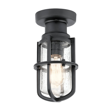 Introducing the Suri Outdoor 1 Light Porch/Pedestal Lantern in Black, featuring a textured industrial-style design with a clear glass shade and metal cage. It showcases an exposed bulb inside, adding nautical charm. This light is mounted on a round base, making it perfect for both indoor and outdoor settings.