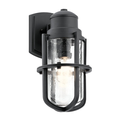 The Suri Outdoor 1 Light Medium Wall Lantern in Black showcases a cylindrical design with clear glass and a dark metal frame. Its visible bulb contributes to an industrial style, while the coastal-inspired lighting provides UV protection for enduring elegance.