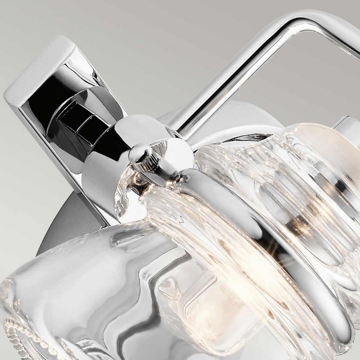 Close-up of the Talland 2 Light Wall Light in polished chrome, showcasing its intricate detailing. The fixture features a curved metal handle and vintage-inspired glasswork, highlighting its sleek and contemporary design.