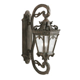 The Tournai Outdoor 4 Light Grand Wall Lantern - Bronze is an ornate, vintage-style outdoor wall lantern with intricate scrollwork and seedy glass panels, mounted on a decorative wall bracket.