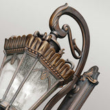 The Tournai Outdoor 4 Light Grand Extra Large Wall Lantern in bronze showcases intricate metalwork with decorative leaf designs, complemented by seedy glass panels. The elegant lantern's vintage touch is enhanced by its bronze finish, standing out beautifully against a soft gray background.