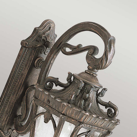 The Tournai Outdoor 1 Light Medium Wall Lantern - Bronze is an elegant, vintage-inspired lantern with a sophisticated aged bronze finish and decorative accents. It showcases intricate scrollwork, leaf designs, and seedy glass panels, making it a delightful addition to any outdoor setting with its antique charm.