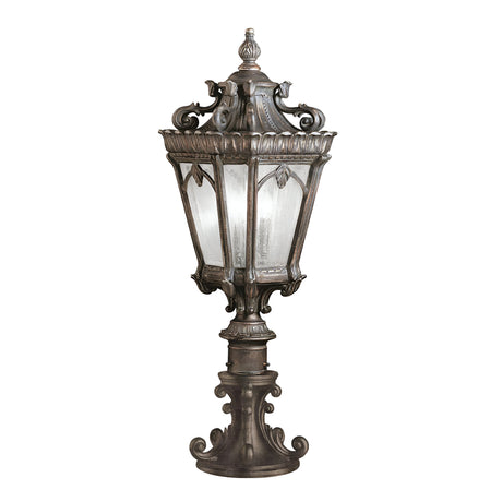 The Tournai 2 Light Large Pedestal lamp features an ornate vintage-style design with a decorative bronze metal frame and clear seedy glass panels, all standing on a detailed pedestal base.