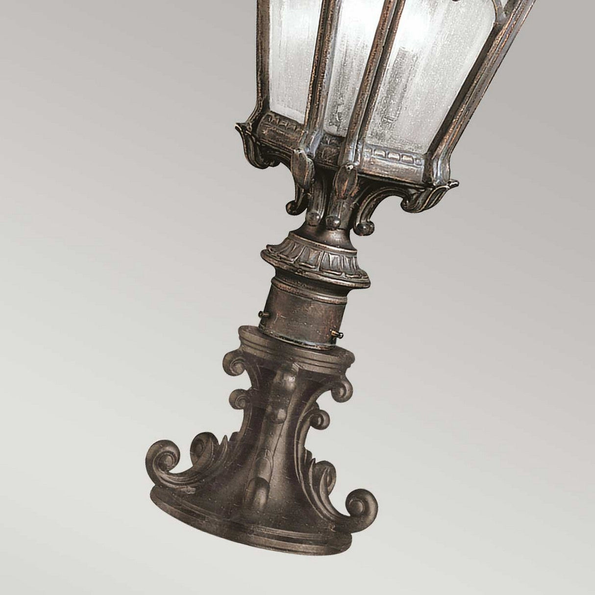 The Tournai 2 Light Large Pedestal in bronze boasts vintage-style design with intricate details and clear seedy glass panels. Diagonally positioned against a neutral backdrop, this outdoor fixture adds a touch of elegance to any space.