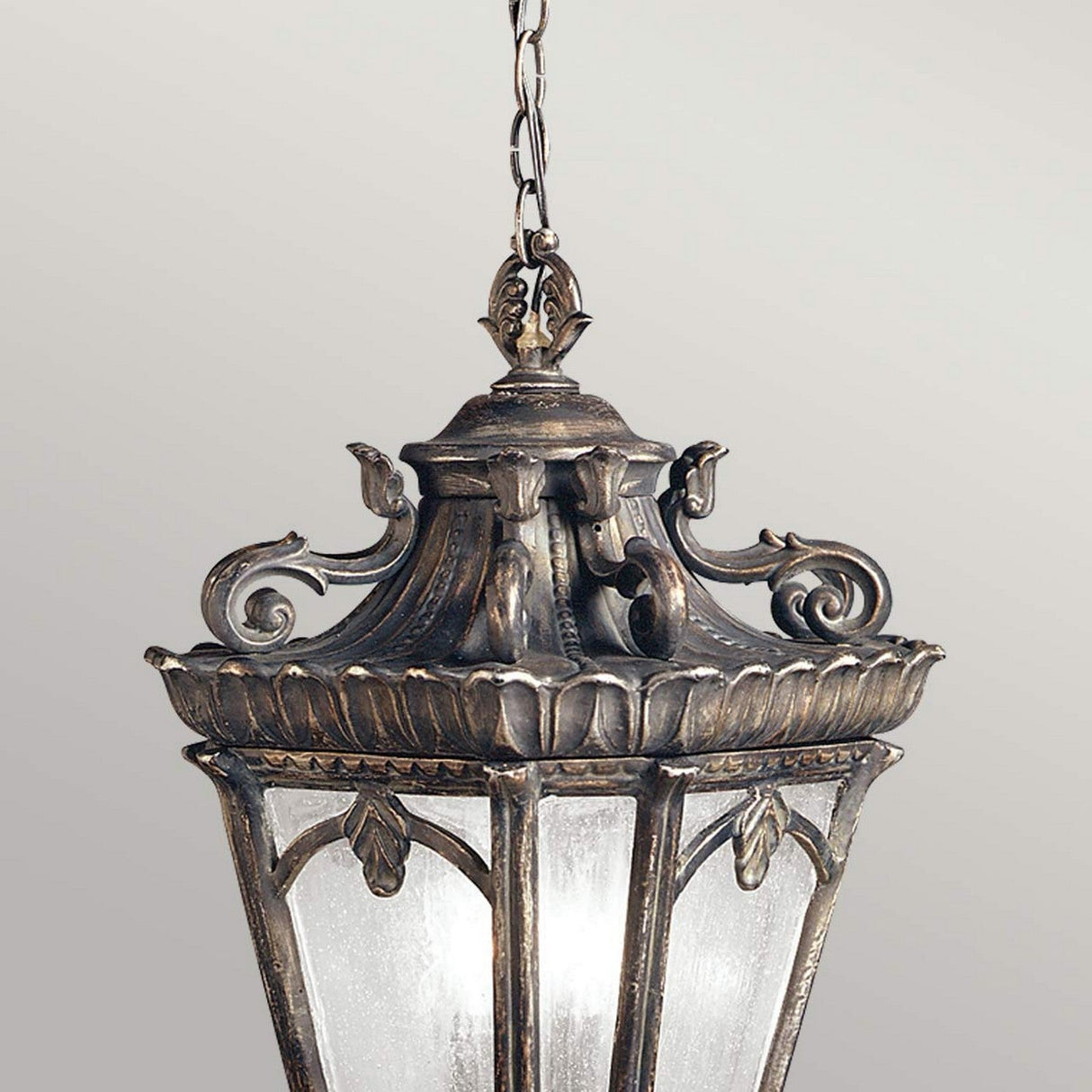 Introducing the Tournai Outdoor 3 Light Extra Large Chain Pendant in Bronze, an ornate hanging European lantern with a vintage design. It boasts intricate scrollwork, a dark bronze finish, frosted glass panels, and is suspended by a decorative bronze chain.