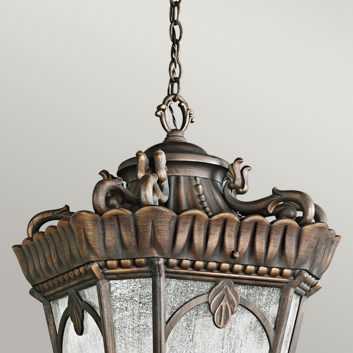 The Tournai Outdoor 4 Light Grand Extra Large Chain Pendant in bronze features an ornate design with a brown antique finish and intricate floral and leaf patterns. This lantern is suspended from a decorative chain, accentuating its vintage charm against a neutral backdrop.