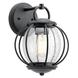The Vandalia Outdoor 1 Light Wall Lantern - Black features a sleek black frame that encases a clear, seeded glass globe. This elegant fixture highlights the light bulb within and is mounted on a circular base plate, bringing an air of sophistication to your exterior decor.