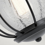 Close-up of the Vandalia Outdoor 1 Light Wall Lantern - Black, featuring raindrop-textured glass. This exterior lighting fixture houses a cylindrical bulb, casting a gentle glow, and is displayed against a simple backdrop.