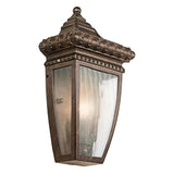 The Venetian Rain Outdoor 1 Light Half Wall Lantern in brushed bronze captures the elegance of a vintage style with its ornate detailing and beveled glass panels, making it a stunning addition to any outdoor space.