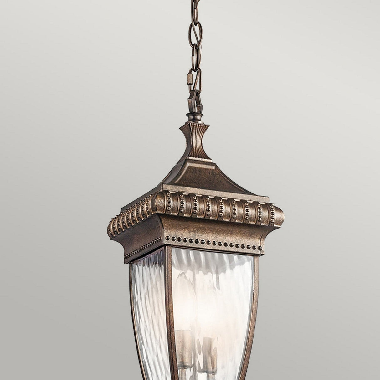 The Venetian Rain Outdoor 2 Light Chain Pendant - Brushed Bronze showcases a vintage-style design with brushed bronze finish and clear rain glass panels, elegantly suspended by a decorative chain against a plain background.