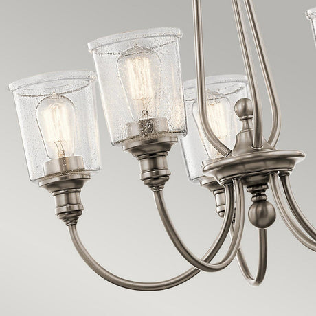 Close-up of the Waverly 5 Light Chandelier - Silver, showcasing its silver finish with multiple arms that extend to seeded glass shades. Each shade holds an exposed bulb, while the metal fixture shines in brushed nickel tones against a light gray background.
