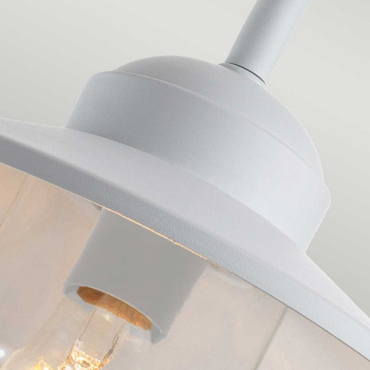 Close-up of the Klampenborg 1 Light Outdoor Wall Light with PIR in white, featuring a transparent glass shade that reveals the bulb inside. This fixture exemplifies Scandinavian design through its smooth matte finish and minimalist aesthetic.