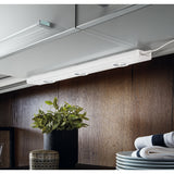 Kob Under Cabinet Light in white steel, a slim bar with three round integrated LED spotlights, shown mounted beneath a kitchen cabinet above a wooden worktop.