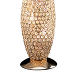 The Kos 3 Light Crystal Table Lamp in French Gold features a gold base and an oval body adorned with sparkling crystal-like gems, casting a warm, glowing light.