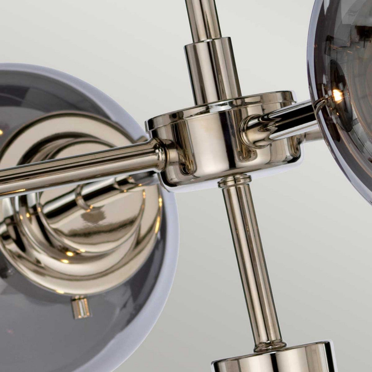 Close-up of the Kula 5 Light Chandelier, featuring spherical glass shades. The fixture showcases sleek, polished rods and smooth joints in a polished nickel finish for a contemporary and elegant appearance.