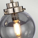 Close-up of the Kula 5 Light Chandelier in Polished Nickel, featuring a modern retro design with round glass shades. The illuminated bulbs inside emit a warm glow, accentuating its sleek elegance.