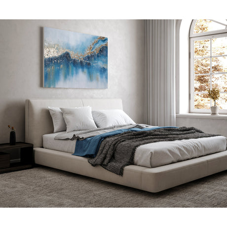 Kunohe Wall Art, a landscape canvas above a bed, abstract misty blue and white design with a diagonal gold and champagne metallic leaf band and navy streaks.