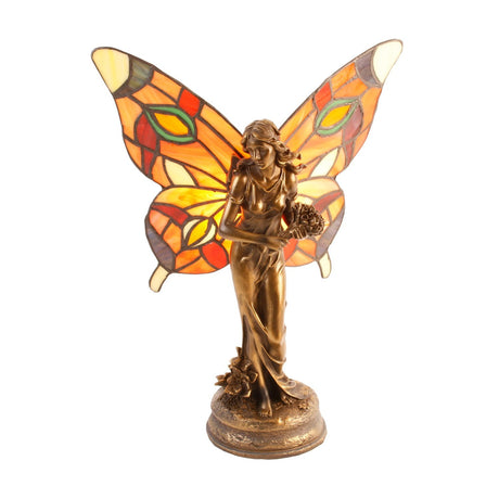 Tiffany-style table lamp shaped as a bronze fairy with stained glass butterfly wings in orange, red and cream tones, holding flowers, on a round base against a plain white background.