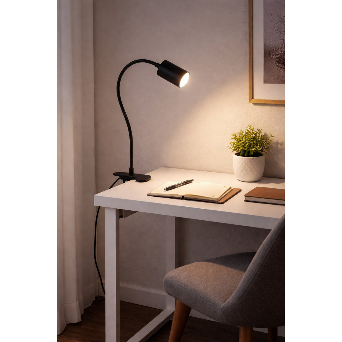 Lardaro Clamp Lamp in black, plastic gooseneck design clipped to a white desk, illuminating an open notebook in a study setting.