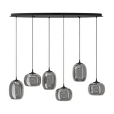 Larva linear pendant light with six smoked glass shades in barrel and globe shapes, staggered heights on black steel cords from an oval ceiling plate, shown on a white background.