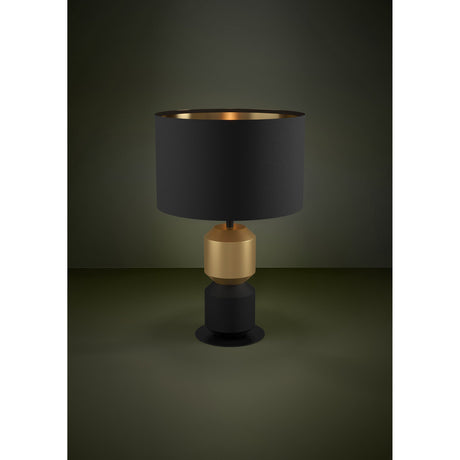 Laurignano Table Lamp in Black & Gold, featuring a black fabric drum shade with gold-lined interior over a faceted gold and black steel body on a round black base.