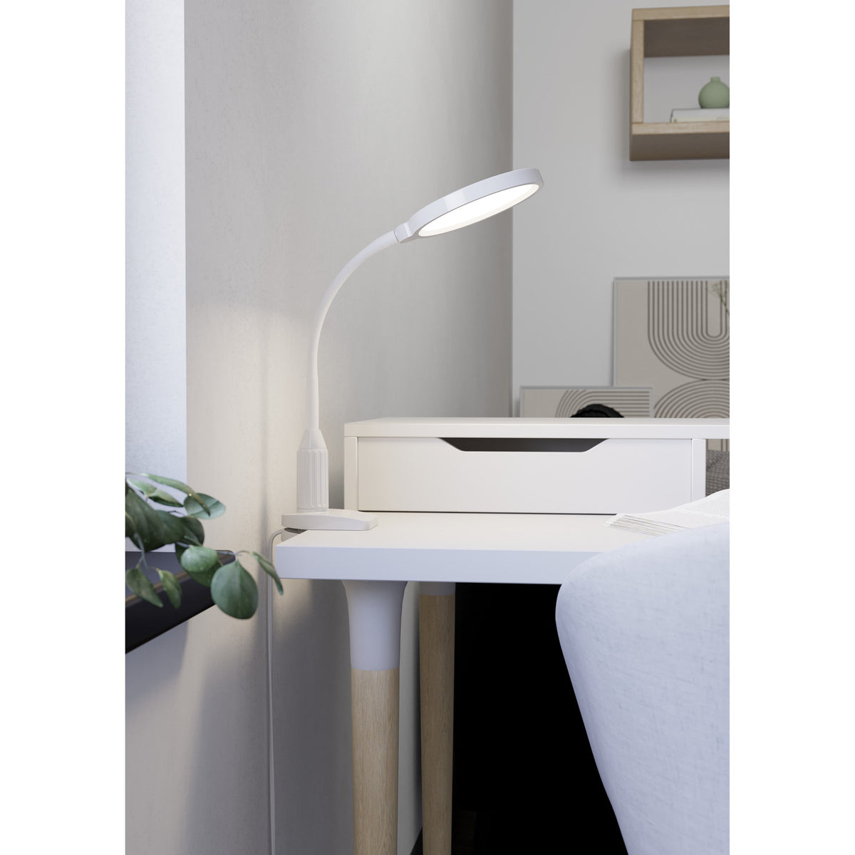 Lauro Clamp Lamp in white, with round LED head on a flexible gooseneck, clamped to the edge of a bedside table in a bedroom setting.