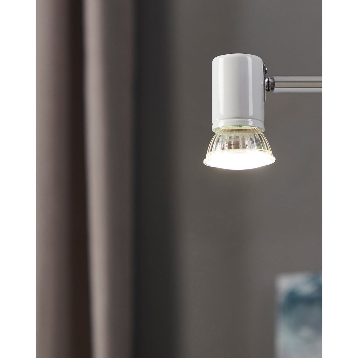 GU10 LED bulb with faceted glass body and satin front, shown lit in a chrome wall light fitting, giving cool white 4000K light.