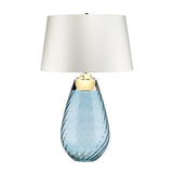 The Lena 2 Light Large Blue Table Lamp showcases an off-white shade and a chic blue glass base with a textured swirl pattern, highlighted by a gold band near the top. This modern design exudes elegance while offering dual-light functionality for customizable lighting.