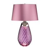 The Lena 2 Light Large Plum Table Lamp with a Heather Shade offers a stylish contemporary design, featuring a light purple mouth-blown glass base embellished with an elegant swirl pattern, and completed by a smooth matching purple shade. This refined piece enhances any room with its sophisticated charm.