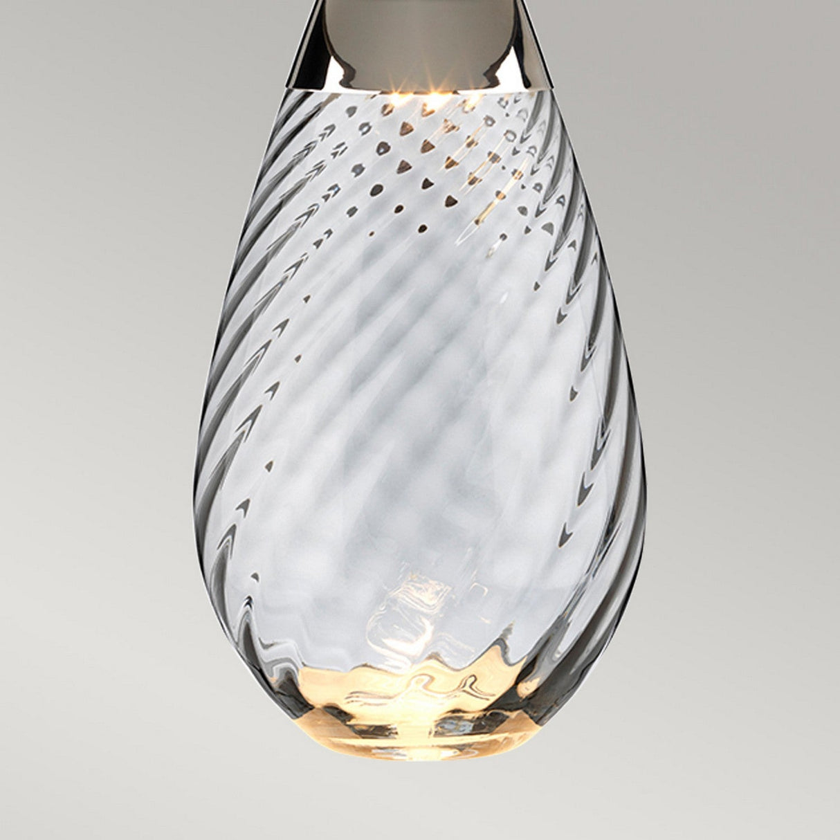 A close-up of the Lena 2 Light Small Blue Table Lamp featuring an off-white shade. The dual-lit system casts a warm glow, highlighting the intricate patterns. The lamp stands against a neutral gray background.