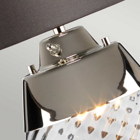 Detailed view of the Lena 2 Light Large Smoke Table Lamp with its sleek metallic design and shiny, reflective surface. The lamp is illuminated, casting a warm glow through its slate shade. The fixture incorporates smoke-tinted glass with a spotted pattern, adding a modern touch to the look.