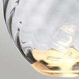A close-up view of a smoke-hued glass piece showcases wavy textures with a transparent surface. The lower section transitions from golden to clear, capturing and reflecting light in an abstract, artistic design akin to the sophisticated style of the Lena 2 Light Large Smoke Table Lamp with Slate Shade. The background is softly colored in neutral tones.
