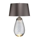 Introducing the Lena 2 Light Large Smoke Table Lamp with a slate shade, featuring a transparent, smoke-tinted glass base with an elegant spiral design. The gray lampshade complements its slightly illuminated Dual-Lit system, adding a touch of sophistication to any room.