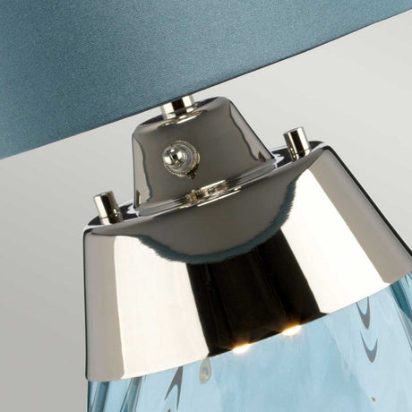 Close-up of a metallic ceiling fixture with a glossy chrome finish, featuring a glass element beneath. The soft gray ceiling enhances the minimalist and modern look, complemented by the subtle elegance of the Lena 2 Light Small Blue Table Lamp with its Duck Egg Blue Shade in nearby decor elements.