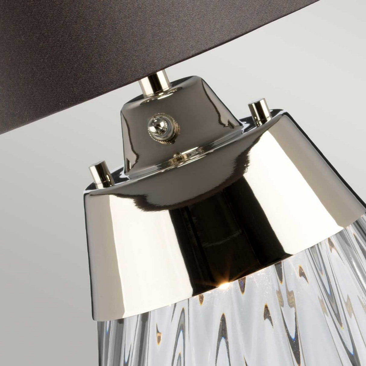 Close-up of the Lena 2 Light Small Smoke Table Lamp - Slate Shade, showcasing its transparent smoke-tinted glass base with shiny metallic accents. The dark slate shade provides a sleek contrast, ideal for contemporary interior decor. Its innovative Dual-Lit system enhances the ambiance.