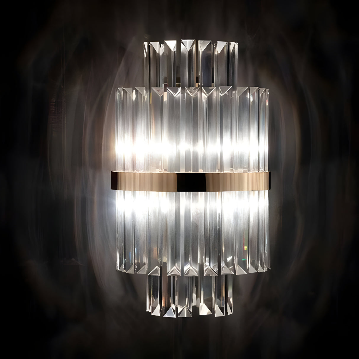 Introducing the Liberty 2 Light Crystal Glass Wall Light in Gold, a contemporary sconce featuring vertical crystal prisms and a stylish gold-finished central metallic band. It emits a soft glow, beautifully reflecting and refracting through the crystal glass against dark settings.