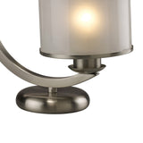 A close-up of the Lincoln 1 Light Crystal Table Lamp in satin nickel, featuring a glass shade softly illuminated with warm light.