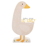 Wooden goose-shaped plaque in beige with white spots, mustard yellow beak and feet, curved neck framing "you are SO LOVELY" text, on a plain white background.