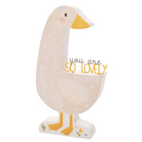Wooden goose-shaped plaque in beige with white spots, mustard yellow beak and feet, rosy cheek, and "you are SO LOVELY" lettering along its back, standing on a flat base against a white background.
