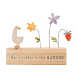 Wooden plaque with "Life is better in the GARDEN" text, featuring a cream goose figure and wire flower stems with yellow, purple blooms and a strawberry, on white background.