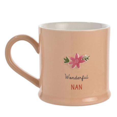 Peach stoneware mug with white interior, featuring an embossed pink flower and green leaves above "Wonderful" in grey script and "NAN" in red capitals, shown on a white background.