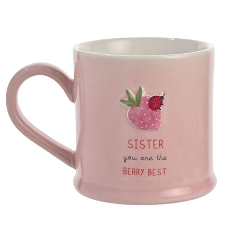 Pink stoneware mug with embossed strawberry and ladybird design, printed "SISTER you are the BERRY BEST" text, white interior, rounded handle, on a plain background.