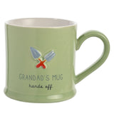 Green stoneware mug with white interior, featuring embossed garden trowel and fork design and "Grandad's Mug, hands off" text, set against a plain white background.