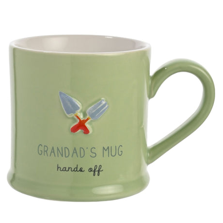 Green stoneware mug with white interior, featuring embossed garden trowel and fork design and "Grandad's Mug, hands off" text, set against a plain white background.