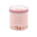 Round pink tin scented candle, 8cm x 8cm, printed with "Sister you are the Berry Best" and strawberry, ladybird and floral illustrations, white lid, plain background.