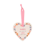 White ceramic heart hanging decoration with floral border and "Grandma, you make the world a better place" text, pink ribbon, plain background.