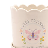 Close-up of the Good Friends Round Stoneware Planter in off white with scalloped rim, featuring a pastel butterfly, flowers and hearts design with "GOOD FRIENDS" text.